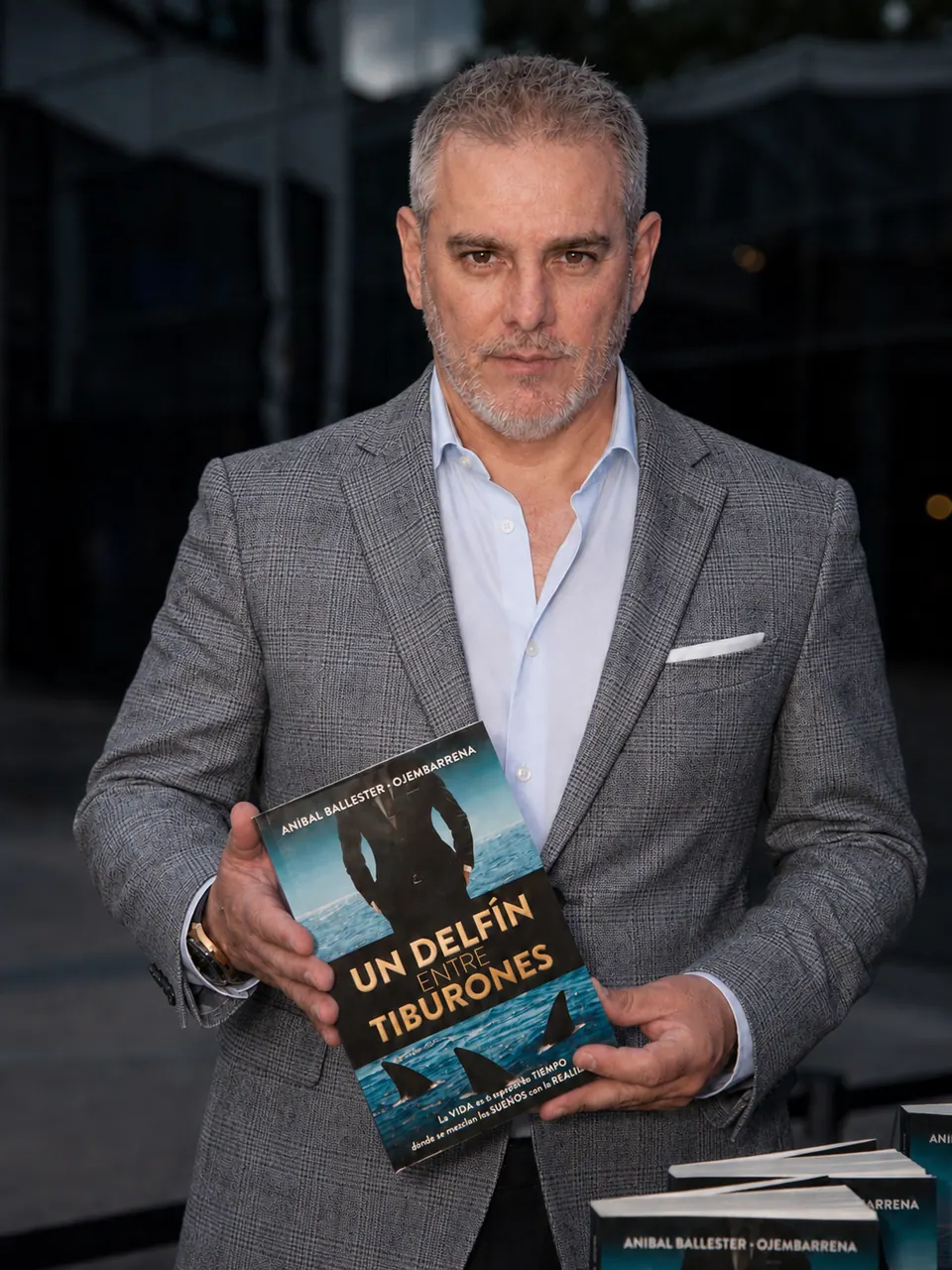Aníbal Ballester sosteniendo su libro Un Delfín entre Tiburones